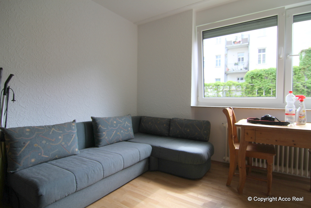 Man sieht die Couchecke und am Fenster einen kleinen Esstisch